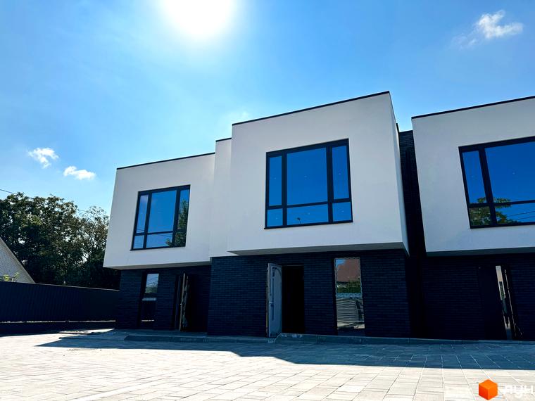 Сучасний житловий комплекс на вул. Троянівська, 21а, з білими фасадами та темною цегляною основою. Перед будинками розташований вимощений бруківкою двір.