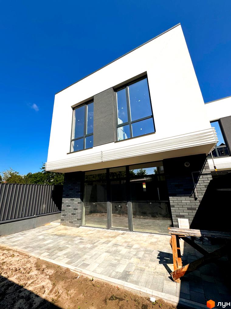 Зовнішній вигляд новобудови на вул. Троянівська, 21а, з панорамними вікнами та брукованою прибудинковою територією.