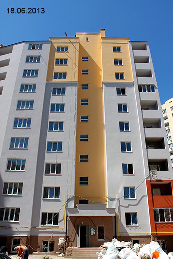 Житловий комплекс вул. Ковалевського, 37. Вид на фасад будинку з жовтими та білими стінами, прибудинкова територія в процесі облаштування.