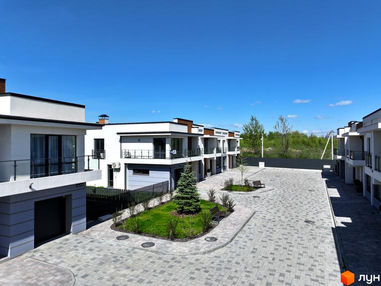 Котеджне містечко City Villa Club. Зовнішній вигляд білих будинків з балконами та прибудинкова територія з бруківкою та зеленими насадженнями.