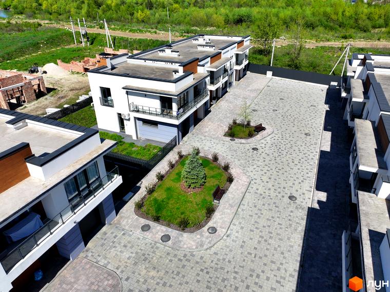 Зовнішній вигляд будинків котеджного містечка КМ City Villa Club з брукованою прибудинковою територією та зеленими зонами. Фото новобудови.