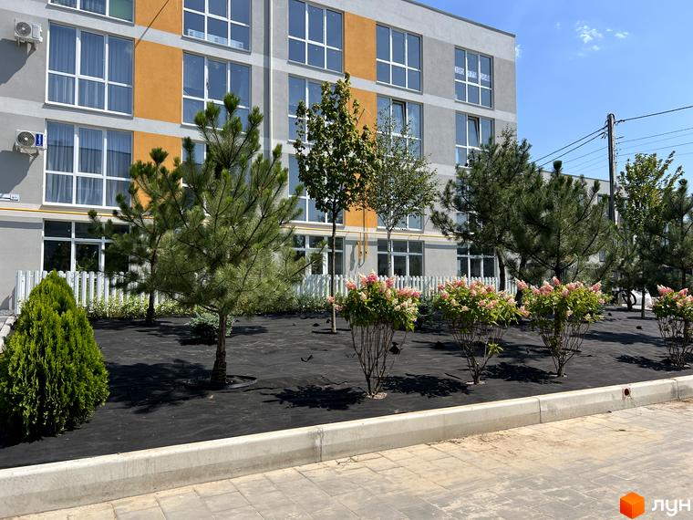 Житловий комплекс Sanville Park: фасади будівель з панорамними вікнами та упорядкована прибудинкова територія з зеленими насадженнями.