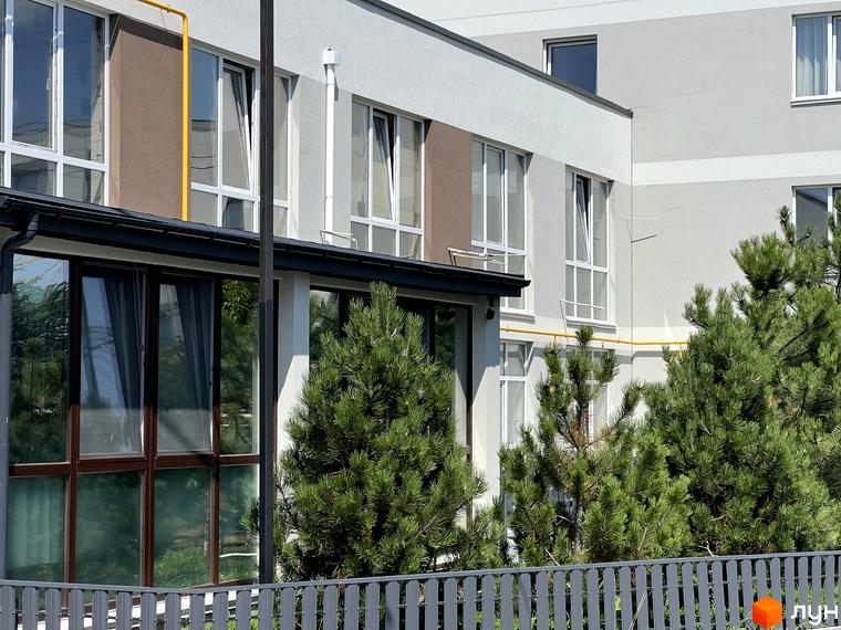 Зовнішній вигляд новобудови ЖК Sanville Park з вікнами та зеленими насадженнями. Зовнішній вигляд будинку та прибудинкової території.