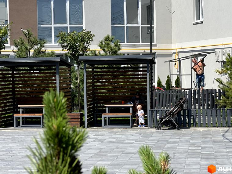 Житловий комплекс Sanville Park. Зовнішній вигляд будинку та прибудинкова територія з альтанками, дитячим майданчиком та місцями для відпочинку.