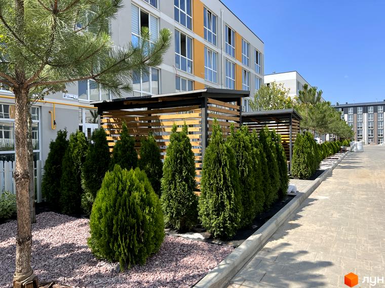 Житловий комплекс Sanville Park: фасади будівель з жовтими акцентами та зелені насадження на прибудинковій території.