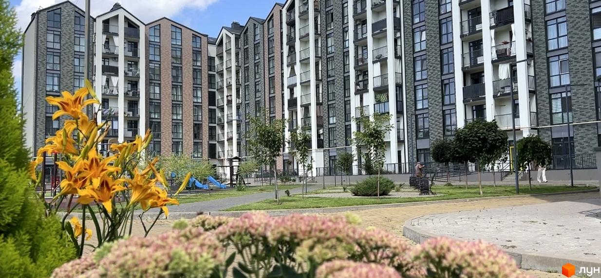 Житловий комплекс ЖК Scandia з фасадами з цегли та білої штукатурки, балконами та дитячим майданчиком на прибудинковій території.