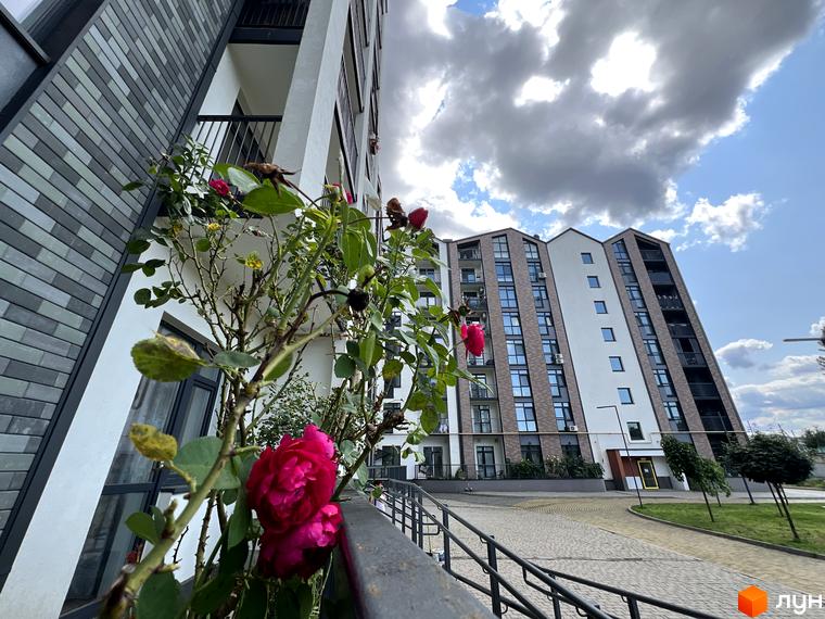 Житловий комплекс Scandia: фасади будинків з цегляним оздобленням та панорамними вікнами. Прибудинкова територія з бруківкою та зеленими насадженнями.