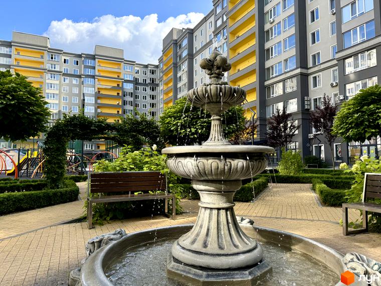 Житловий комплекс Millennium State з сірими фасадами та жовтими балконами, прибудинкова територія з фонтаном, лавками та зеленню.