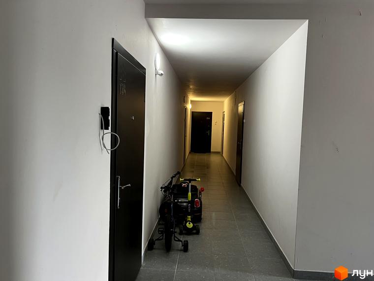 Коридор з дверима в ЖК Scandia. На зображенні видно двері з номером 148 та дитячий триколісний велосипед.