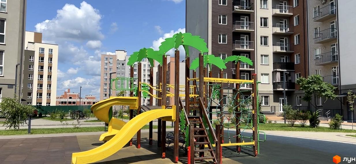 Житловий комплекс Scandia: дитячий майданчик з гірками та мотузковим містечком на тлі багатоповерхових будинків.