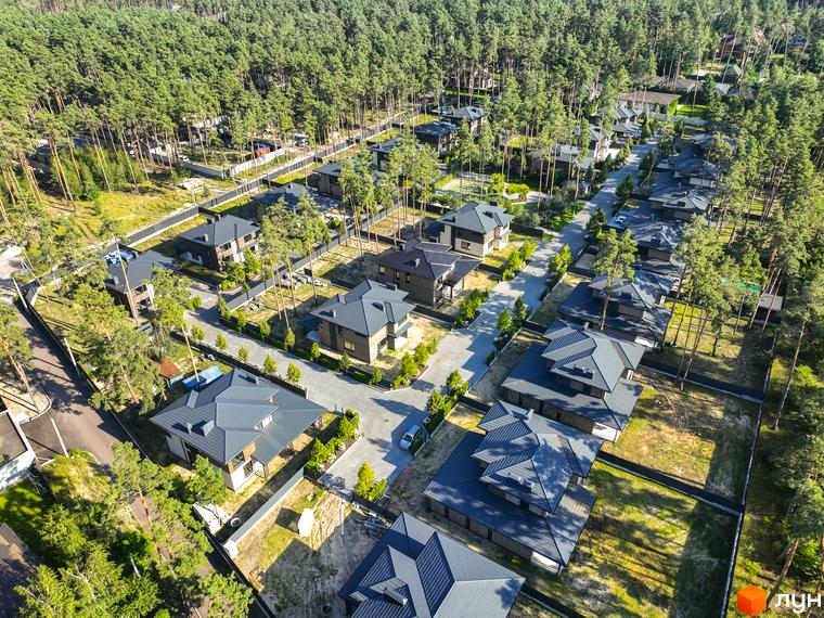Котеджне містечко ZAHRAVA village 2: сучасні будинки з темними дахами серед соснового лісу. Прибудинкова територія з доглянутими газонами та деревами.