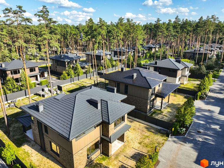 Котеджне містечко ZAHRAVA village 2. Сучасні будинки з темними дахами та цегляними фасадами, розташовані серед високих сосен.