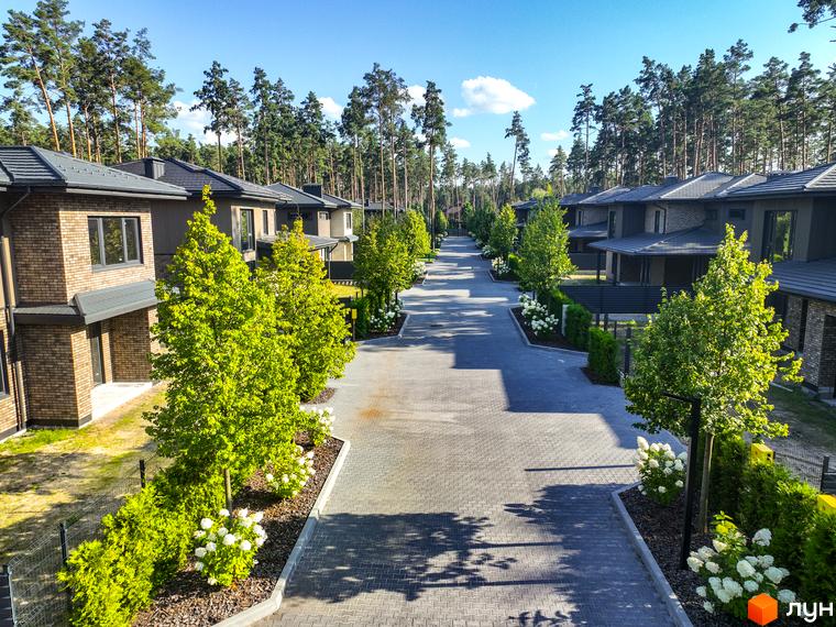 Котеджне містечко ZAHRAVA village 2: сучасні будинки з цегли та дерева, доглянута прибудинкова територія з деревами та квітами.