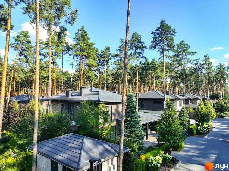 Котеджне містечко ZAHRAVA village 2. Будинки з сірими дахами та цегляними фасадами, розташовані серед високих сосен. Прибудинкова територія з доглянутими зеленими насадженнями та доріжками.