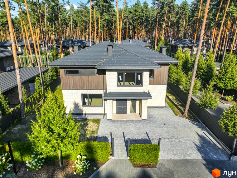 Котеджне містечко ZAHRAVA village 2: двоповерховий будинок з білої цегли та дерев'яними вставками, сірим дахом, розташований на бруківці з акуратними кущами та деревами.