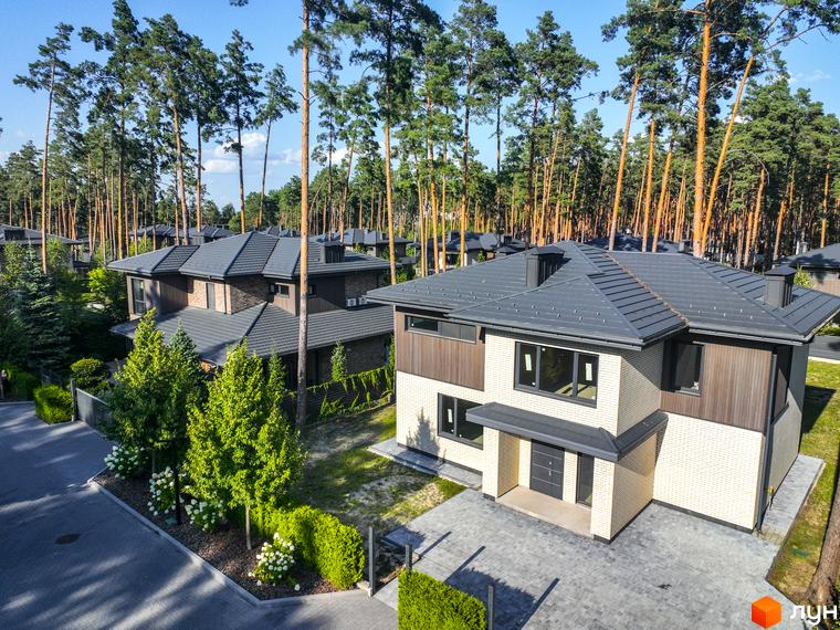 Котеджне містечко ZAHRAVA village 2. Зовнішній вигляд двоповерхових будинків з темним дахом та світлими стінами, прибудинкова територія з деревами та кущами.