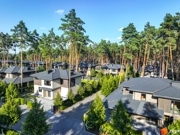 Котеджне містечко ZAHRAVA village 2. Зовнішній вигляд двоповерхових будинків з темними дахами та цегляними фасадами, оточених соснами та зеленими насадженнями.