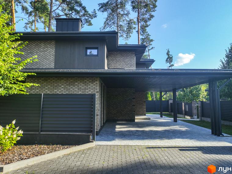 Котеджне містечко ZAHRAVA village 2. Фасад будинку з цегли та дерев'яних панелей, навіс для авто та бруківка.