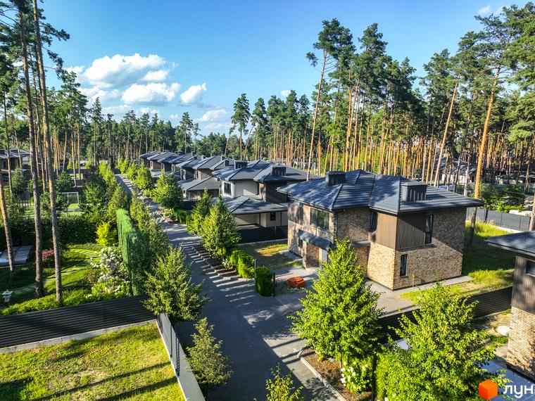 Котеджне містечко ZAHRAVA village 2. Сучасні будинки з цегляним фасадом та темним дахом, розташовані серед високих сосен. Доглянута прибудинкова територія з зеленими насадженнями.