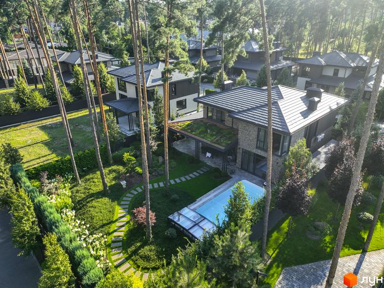 Котеджне містечко ZAHRAVA village 2: двоповерховий будинок з цегляним фасадом, зеленою покрівлею та басейном. Навколо будинку доглянутий сад з доріжками та деревами.