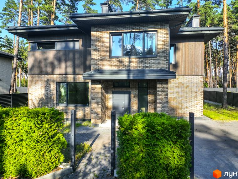 Котеджне містечко ZAHRAVA village 2: двоповерховий будинок з цегляним фасадом, великими вікнами та зеленою прибудинковою територією з кущами та парканом.