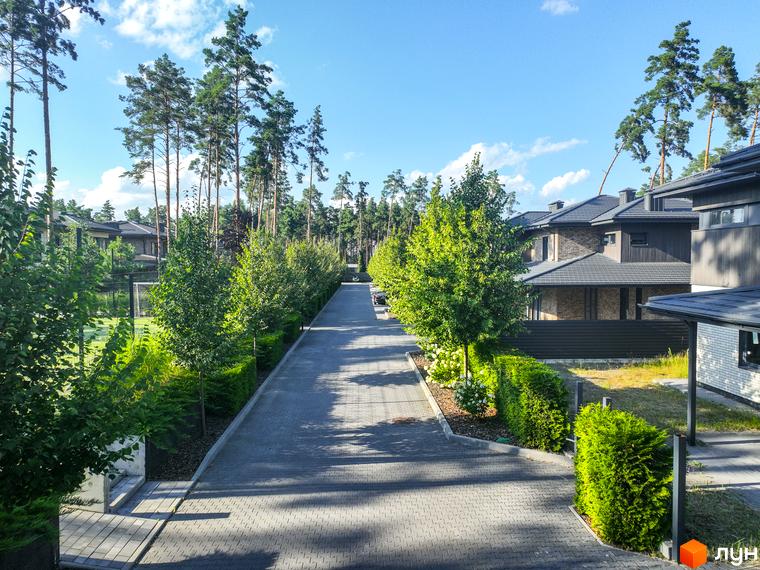 Котеджне містечко ZAHRAVA village 2. Асфальтована дорога з акуратними зеленими насадженнями та сучасними будинками.