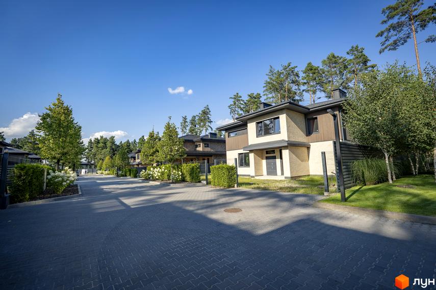 Котеджне містечко ZAHRAVA village 2. Зовнішній вигляд двоповерхових будинків з цегли та дерева, розташованих вздовж вимощеної дороги з зеленими насадженнями.