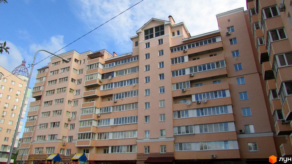 Фасад житлового комплексу просп. Шевченка, 6а, з численними вікнами та балконами. На передньому плані дитячий майданчик.