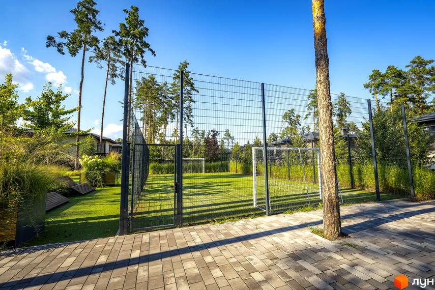 Котеджне містечко ZAHRAVA village 2 з футбольним полем та зеленим ландшафтом. На території розташовані дерева, кущі та зони відпочинку.