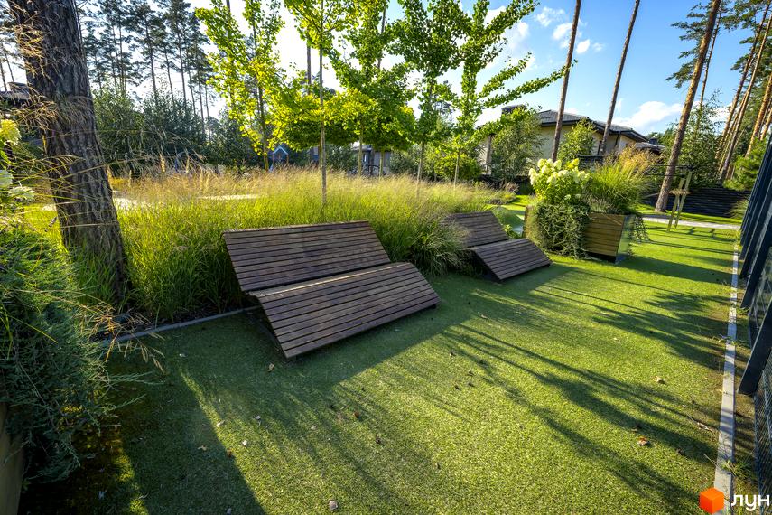 Котеджне містечко ZAHRAVA village 2. Зелена прибудинкова територія з дерев'яними лежаками та декоративними травами.