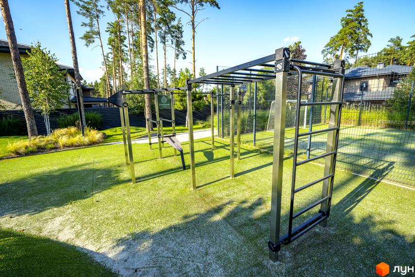 Котеджне містечко ZAHRAVA village 2 з зоною для тренувань на відкритому повітрі та футбольним полем. Навколо зелені насадження та будинки.