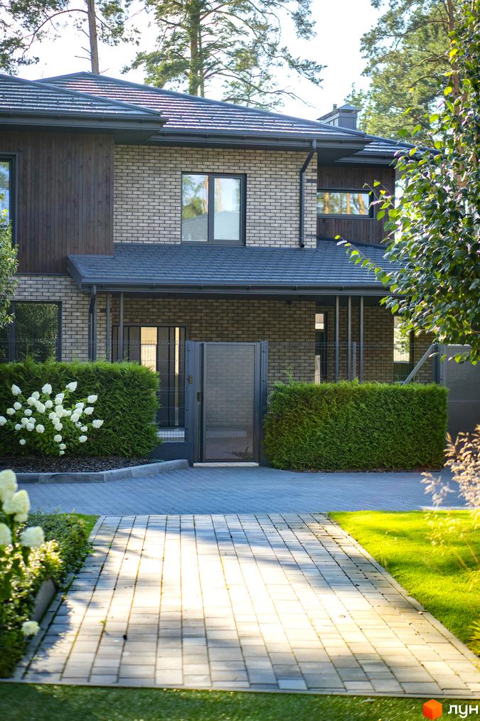 Котеджне містечко КМ ZAHRAVA village 2. Фасад будинку з цегли та дерева, доглянута прибудинкова територія з бруківкою та зеленню.