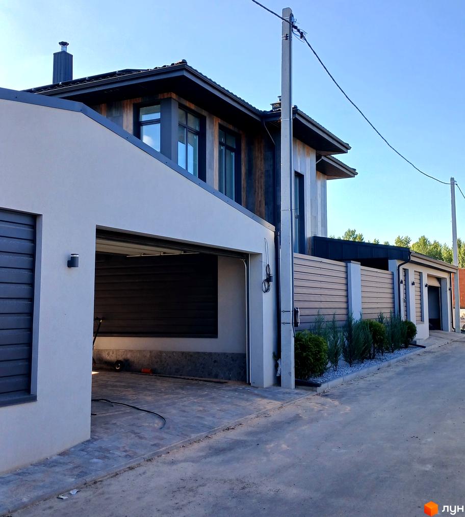 Будинок з гаражем та парканом на вулиці Зелений Гай. Територія комплексу з зеленими насадженнями та бруківкою.