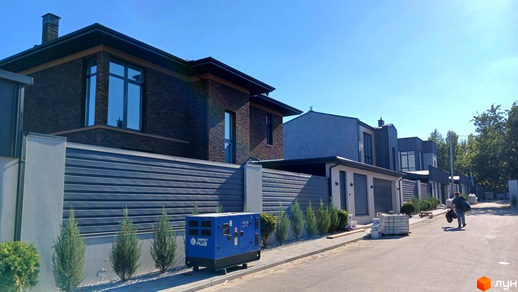 Будинок з цегляним фасадом та великими вікнами на вулиці Зелений Гай. Поряд паркан та зелені насадження.