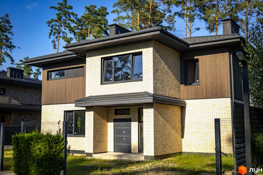 Котеджне містечко ZAHRAVA village 2. Зовнішній вигляд двоповерхового будинку з цегляним фасадом та дерев'яними вставками, зелена прибудинкова територія.