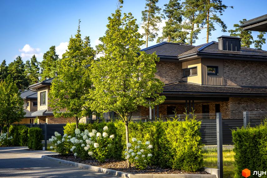 Котеджне містечко ZAHRAVA village 2. Фасад будинку з цегли, зелені насадження та доглянута прибудинкова територія.