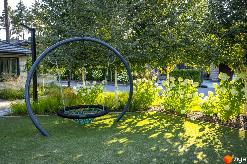 Котеджне містечко ZAHRAVA village 2. Затишна прибудинкова територія з гойдалкою та квітучими кущами.