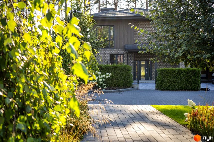 Котеджне містечко КМ ZAHRAVA village 2. Фасад будинку з цегли та дерева, прибудинкова територія з бруківки та зелених насаджень.