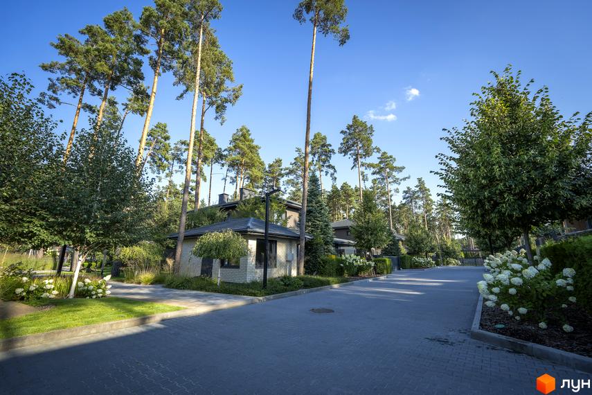 Котеджне містечко ZAHRAVA village 2. Будинки з цегли та дерева серед високих сосен, доглянута прибудинкова територія з газоном та квітами.