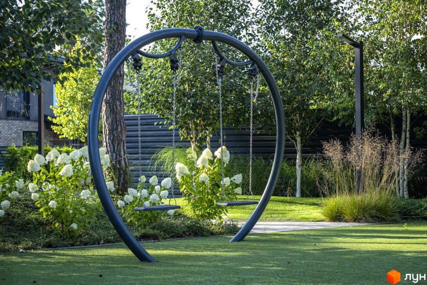 Котеджне містечко ZAHRAVA village 2: сучасний дитячий майданчик з гойдалками на тлі зеленого ландшафту та будинків.