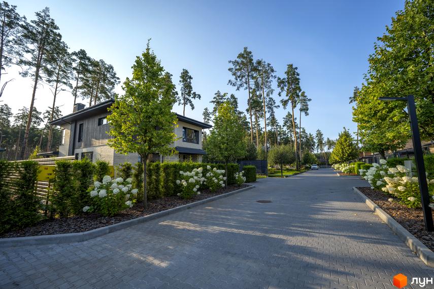 Котеджне містечко ZAHRAVA village 2: двоповерхові будинки з дерев'яними фасадами та цегляними елементами, оточені зеленню та квітучими кущами.