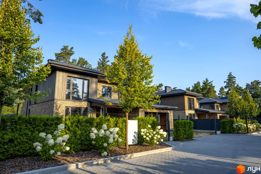 Котеджне містечко ZAHRAVA village 2: двоповерхові будинки з цегляним та дерев'яним фасадом, великими вікнами, оточені зеленню та квітучими кущами.