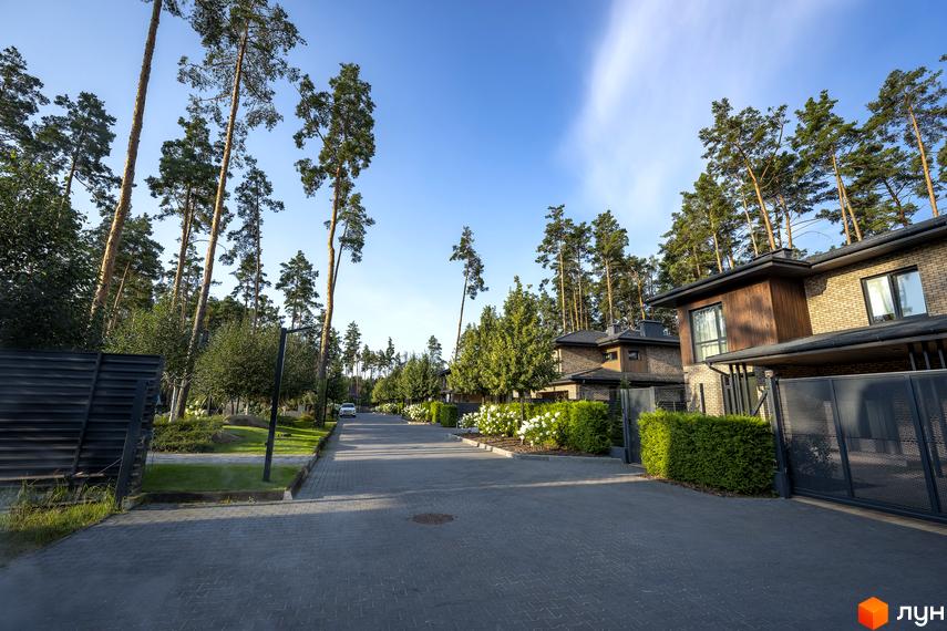 Котеджне містечко ZAHRAVA village 2: цегляні будинки з дерев'яними елементами та доглянута прибудинкова територія з алеєю та зеленими насадженнями.