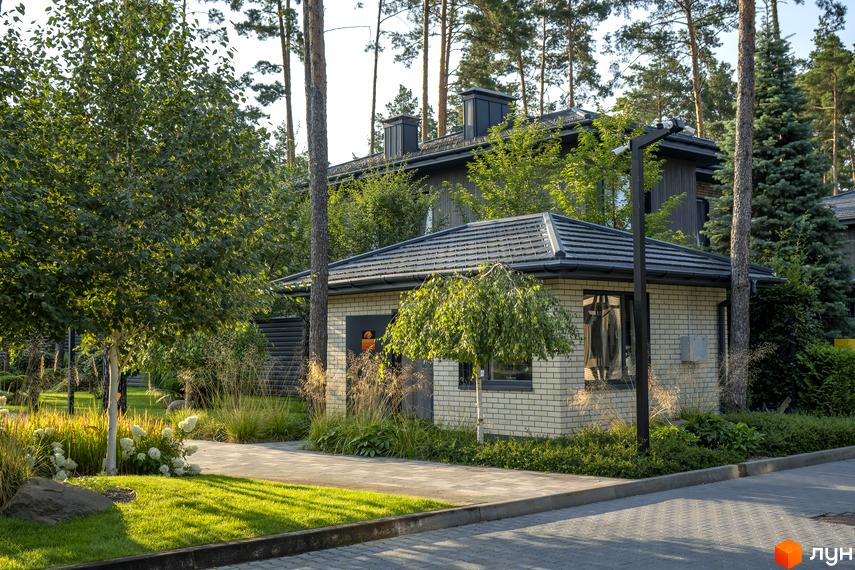 Котеджне містечко ZAHRAVA village 2. Зовнішній вигляд будинку з цегляним фасадом та сірим дахом, оточений деревами та доглянутою прибудинковою територією.