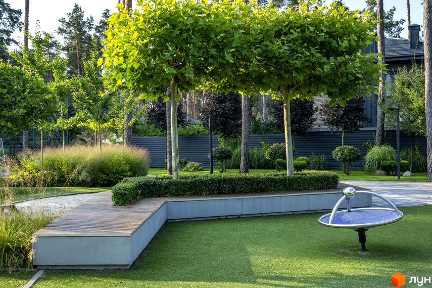 Котеджне містечко КМ ZAHRAVA village 2. Зелена прибудинкова територія з деревами, кущами та дитячим майданчиком.