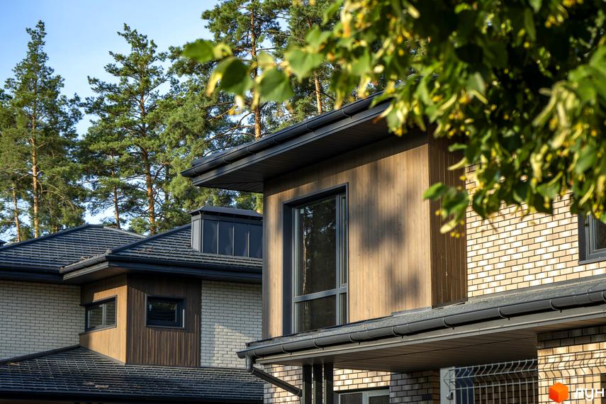 Котеджне містечко КМ ZAHRAVA village 2. Фасади будинків оздоблені дерев'яними панелями та світлою цеглою, на тлі високих сосен.