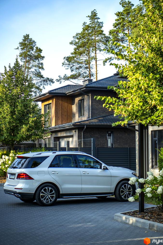 Котеджне містечко ZAHRAVA village 2: сучасна архітектура будинку з цегляним фасадом та прибудинковою територією з білим автомобілем.