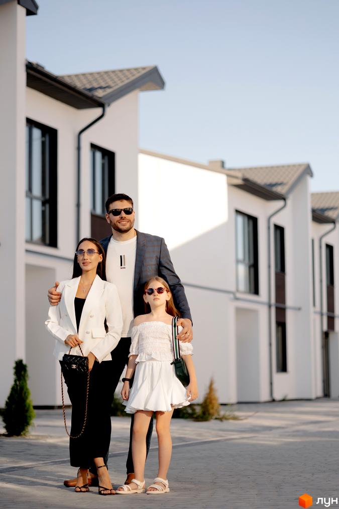 Котеджне містечко КМ WEST TOWN XIV: фасади будинків з великими вікнами та прибудинкова територія з доглянутими зеленими насадженнями.