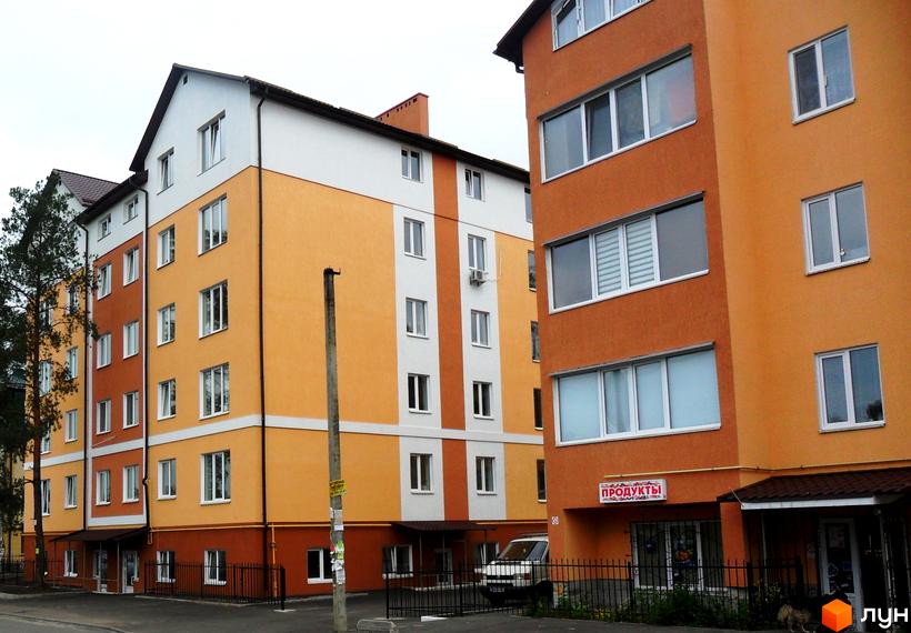 Зовнішній вигляд новобудови на вул. Степанівська, 10а, з яскравими фасадами та вікнами. Поруч видно паркан та дерева.