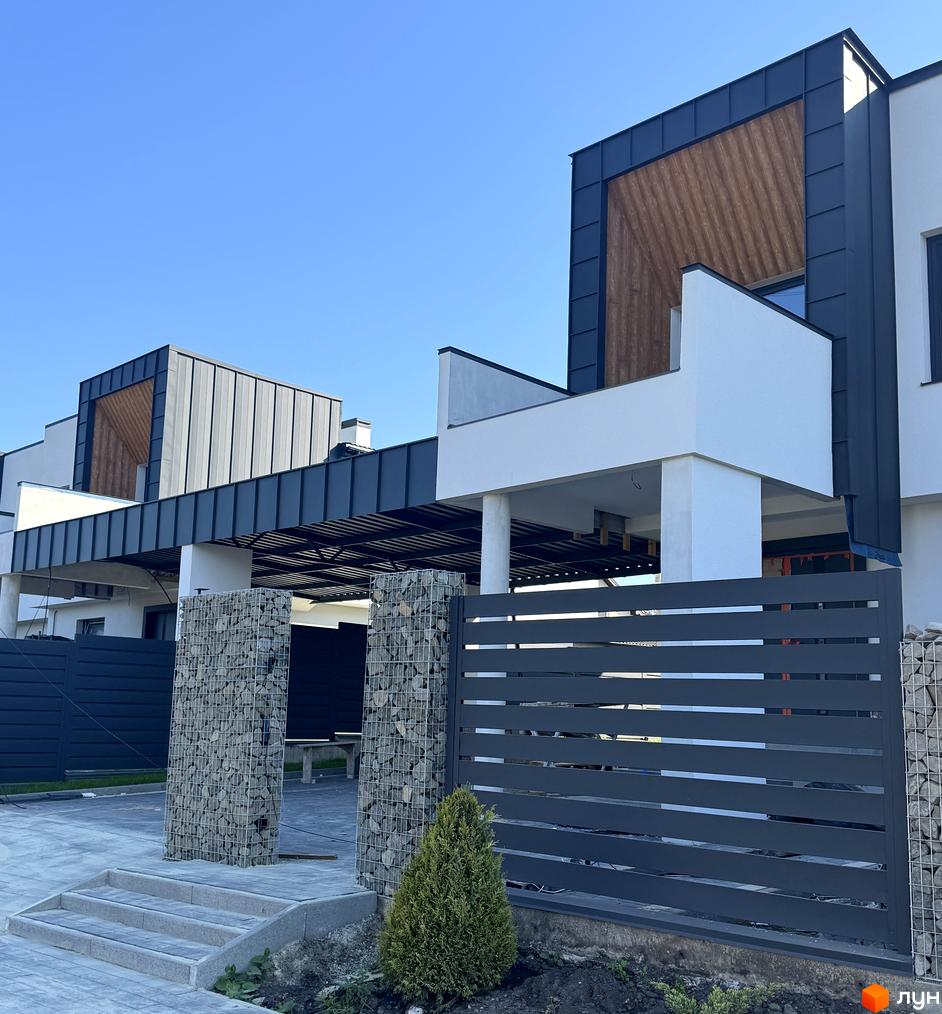 Котеджне містечко Lake House Sokilnyky: фасади будинків з темним металевим покриттям та дерев'яними вставками, сірі паркани та кам'яні колони.